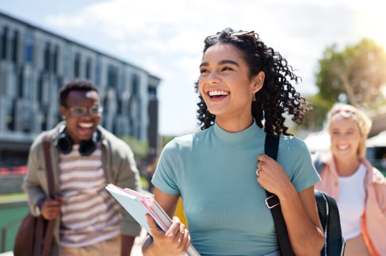 A multicultural group of happy cheerful students walking across the university campus