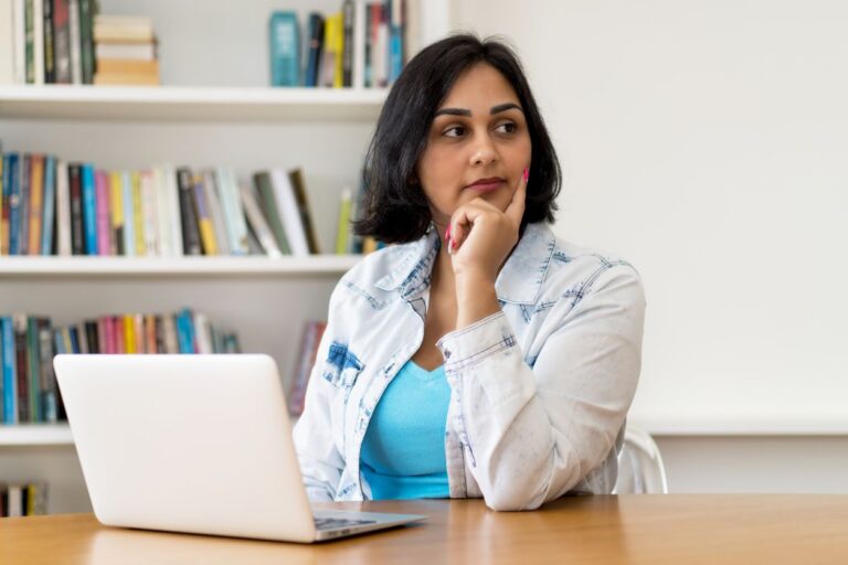 A concerned woman sitting at a table with a laptop